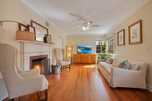 Un salon avec une cheminée, un téléviseur, un canapé et un ventilateur de plafond.