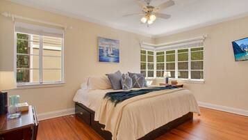 A bedroom with a bed, a ceiling fan, and two windows.