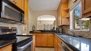 A modern kitchen with wooden cabinets, a stainless steel microwave, an oven, and a sink. - Home away from home in the heart of charming Winter Park! (Winter Park)