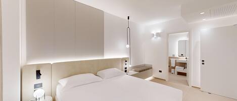 A modern bedroom with a large bed, bedside tables, a built-in bench, and a bathroom with a mirror and sink.