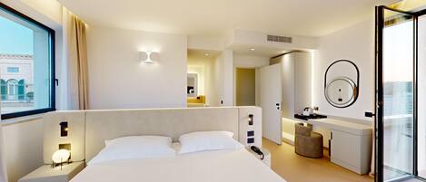 Una habitación de hotel moderna con una cama grande, lámparas de noche, un tocador con espejo y vistas de la ciudad a través de un ventanal.