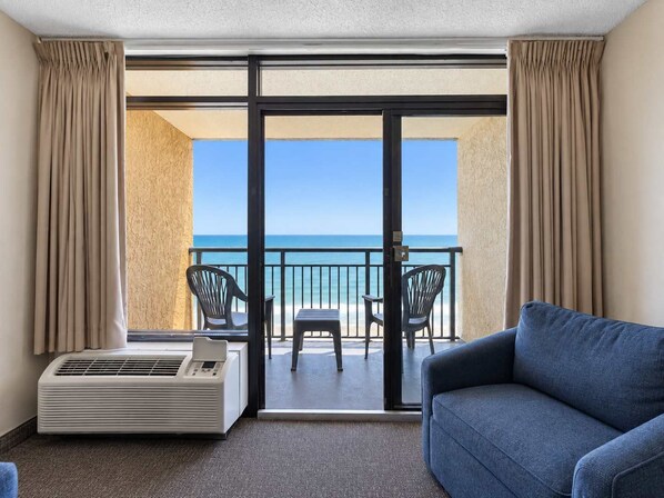 A balcony with a view of the sea, a blue sofa, and a table with chairs.