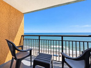 Een balkon met uitzicht op de oceaan, twee stoelen en een kleine tafel.