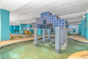 A pool with a unique tiled structure in the center, surrounded by turquoise walls and a clear pool area.