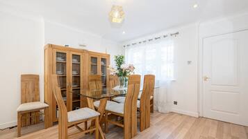 A dining area with a glass table, wooden chairs, and a cabinet with glass doors.
