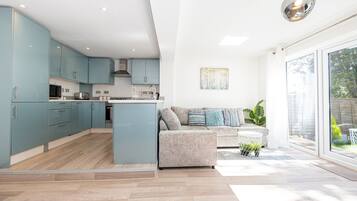 A modern kitchen with light blue cabinets, a central island, and a dining area with a sofa and coffee table.