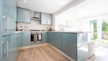 A modern kitchen with glass cabinets, a built-in oven, and a large window offering a view of the outdoors.