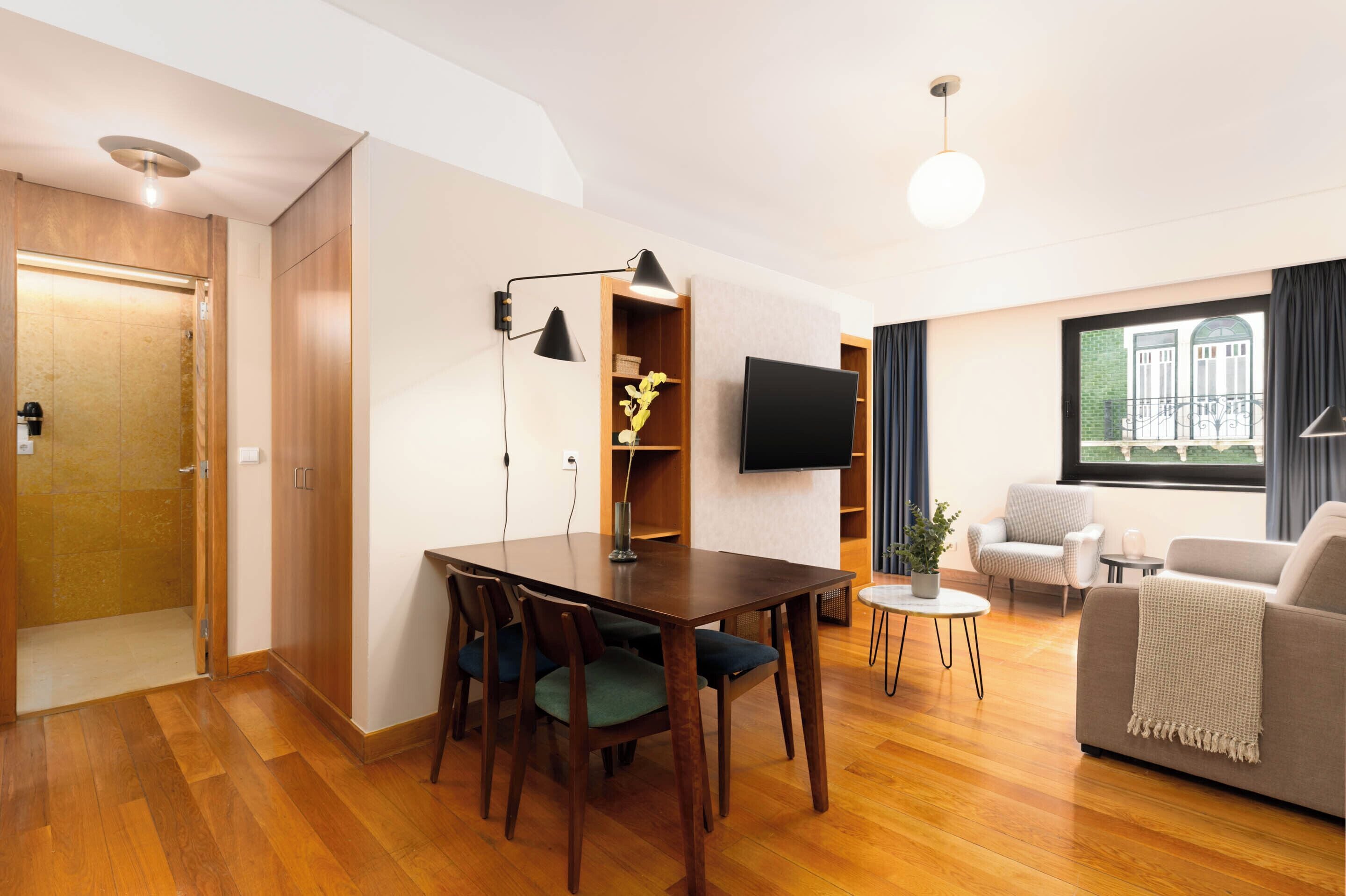 Een moderne woonkamer met een houten eettafel, stoelen, een bank en een televisie.