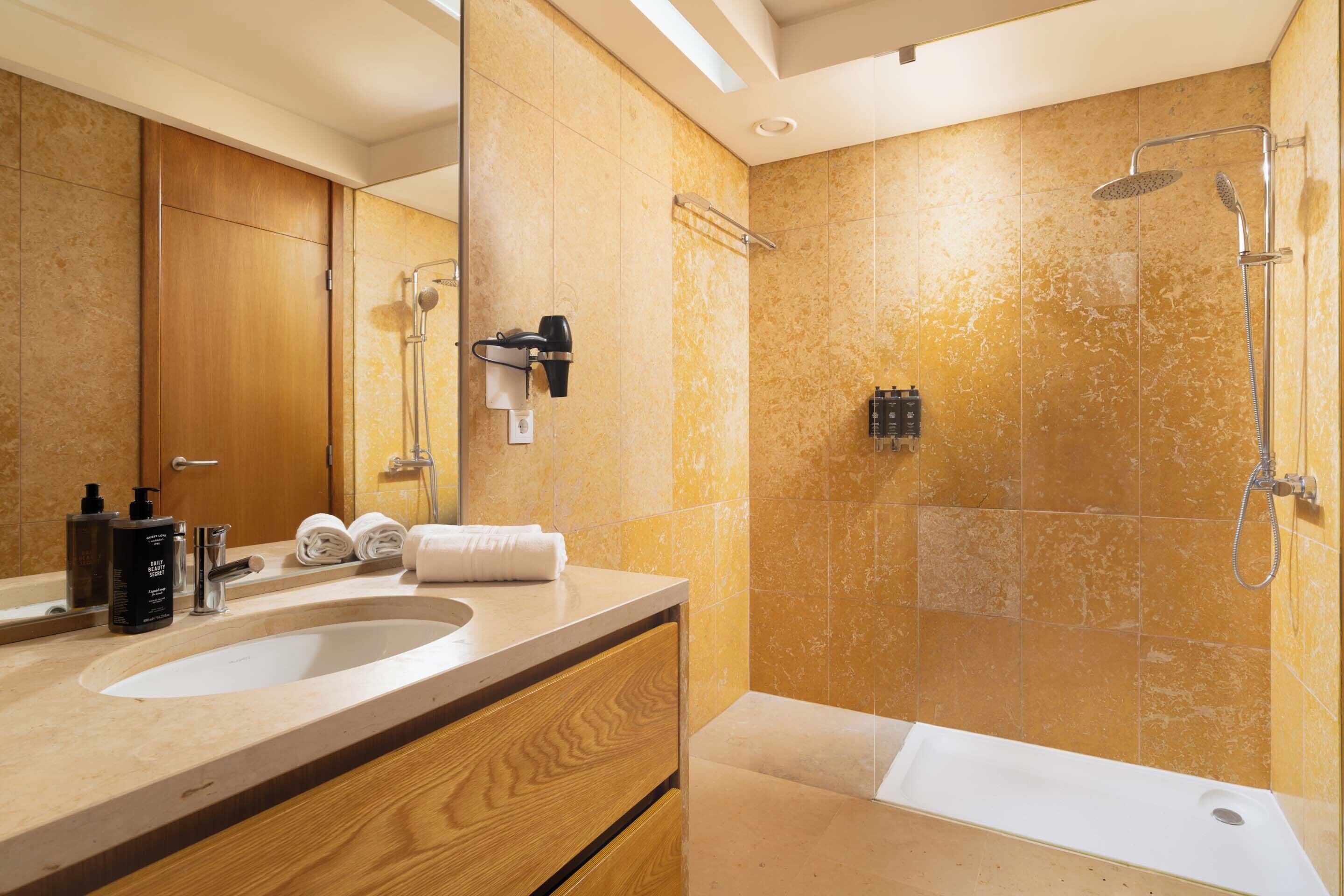 A modern bathroom with dual sinks, a large mirror, and a walk-in shower.