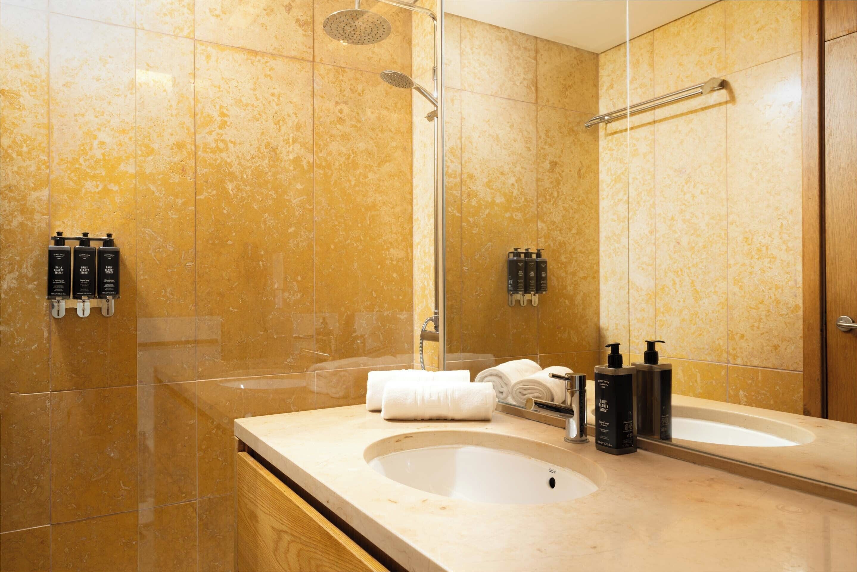 A modern bathroom with a large sink, a mirror, and a shower.