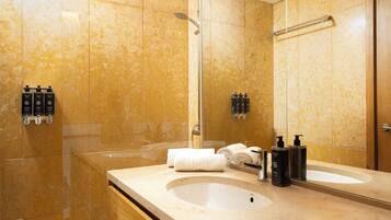 A modern bathroom with a large sink, a mirror, and a shower.