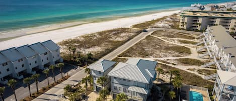 A coastal hotel with a beach view, multiple buildings, and a swimming pool.