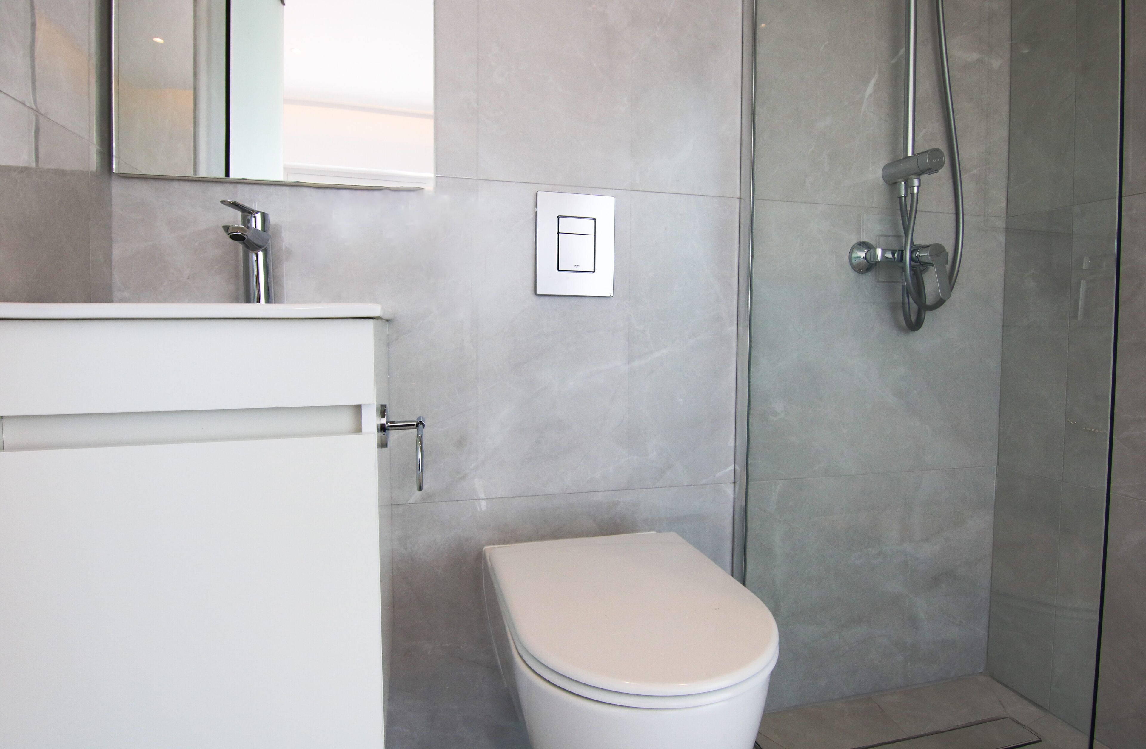 A modern bathroom with a toilet, a shower, and a mirror.