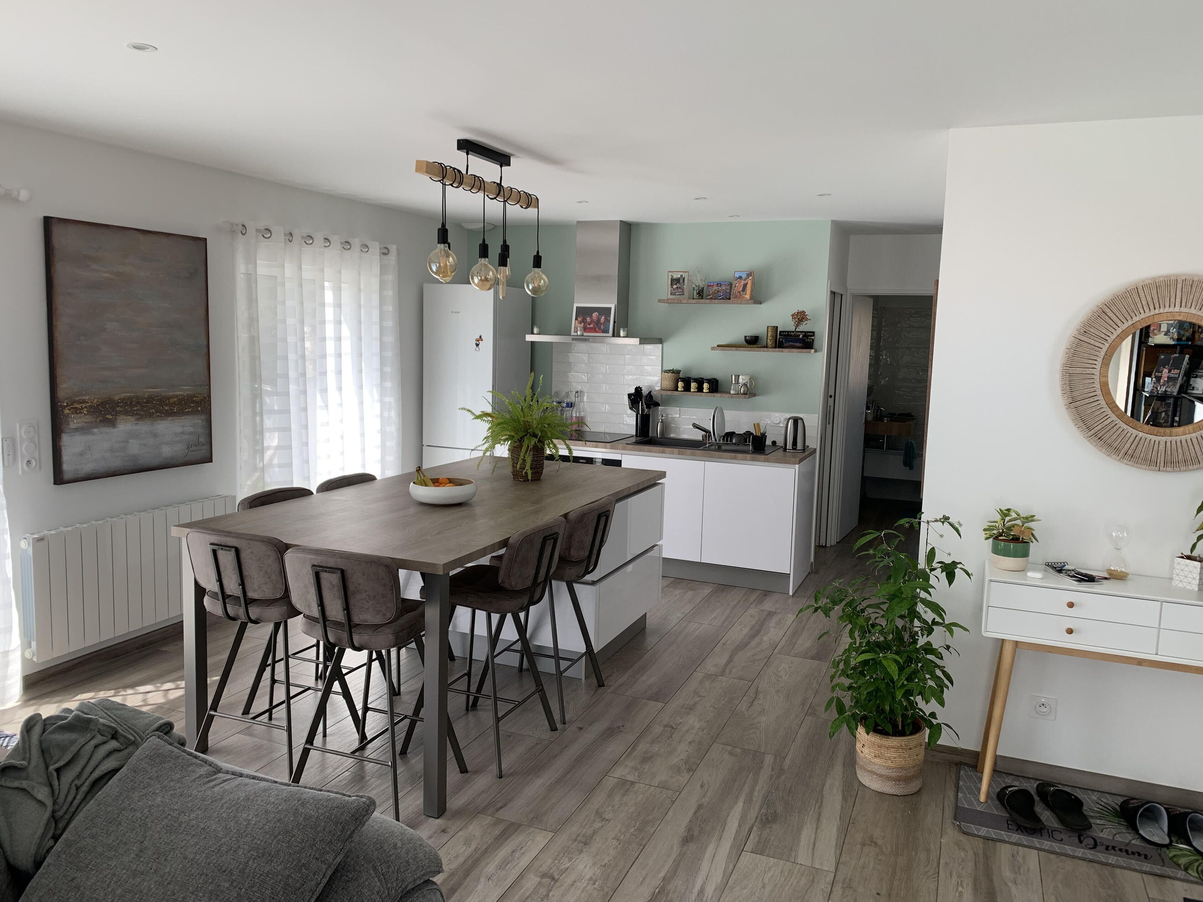 Een moderne keuken met een eettafel, stoelen en een hangende lamp.