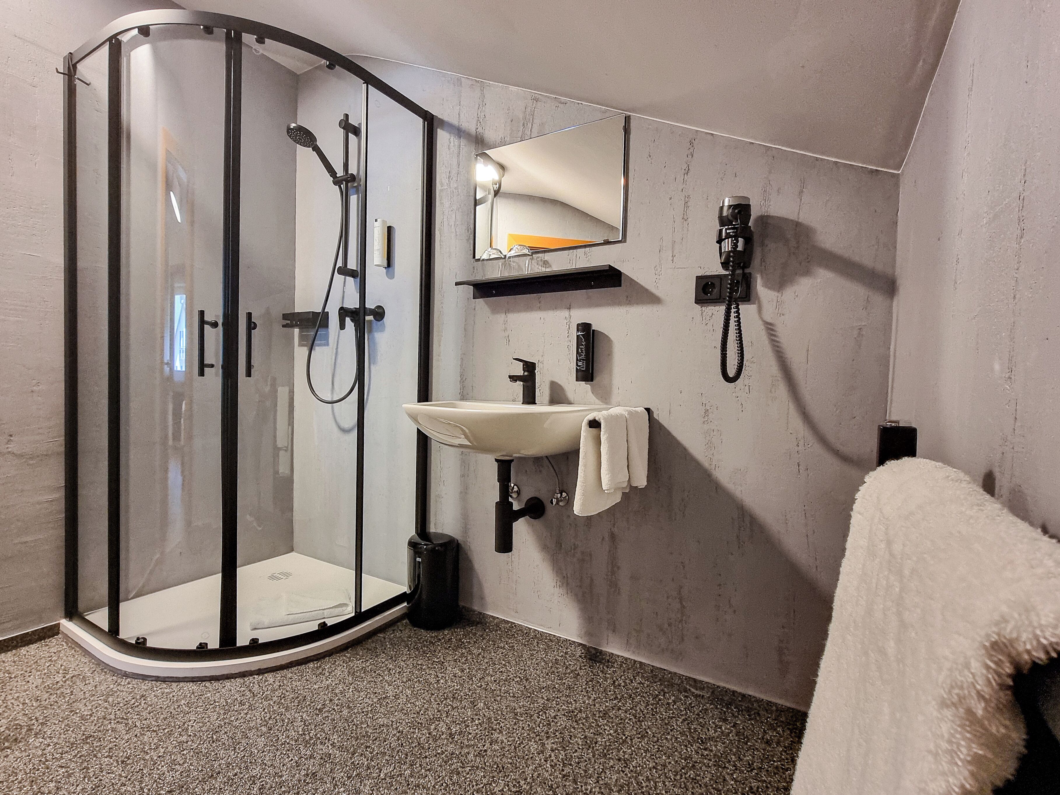 Une salle de bain moderne avec une douche à parois de verre, un lavabo avec une serviette et un miroir.