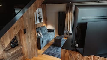 Un salon moderne avec un escalier en bois, un canapé gris et un téléviseur à écran plat.