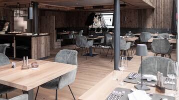 A modern restaurant with wooden accents, grey upholstered chairs, and a clean, minimalist design.