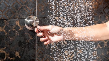 Eine Hand dreht einen Wasserhahn, Wasser sprudelt heraus.