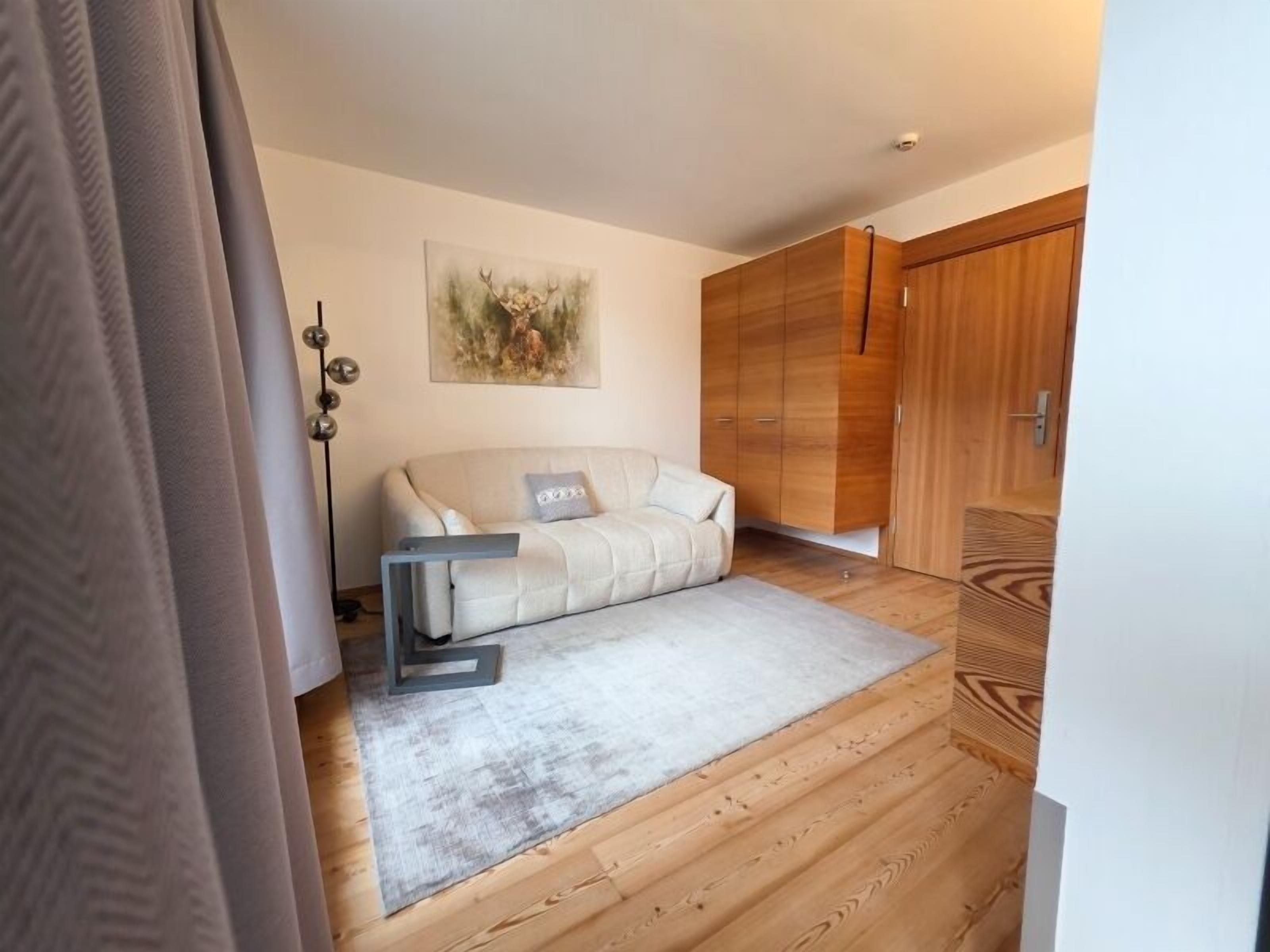 Una habitación con sofá, lámpara de pie y suelo de madera.