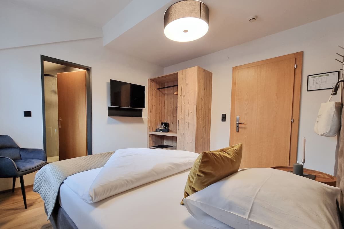 Habitación de hotel con dos camas, televisión, armario de madera y escritorio con lámpara.