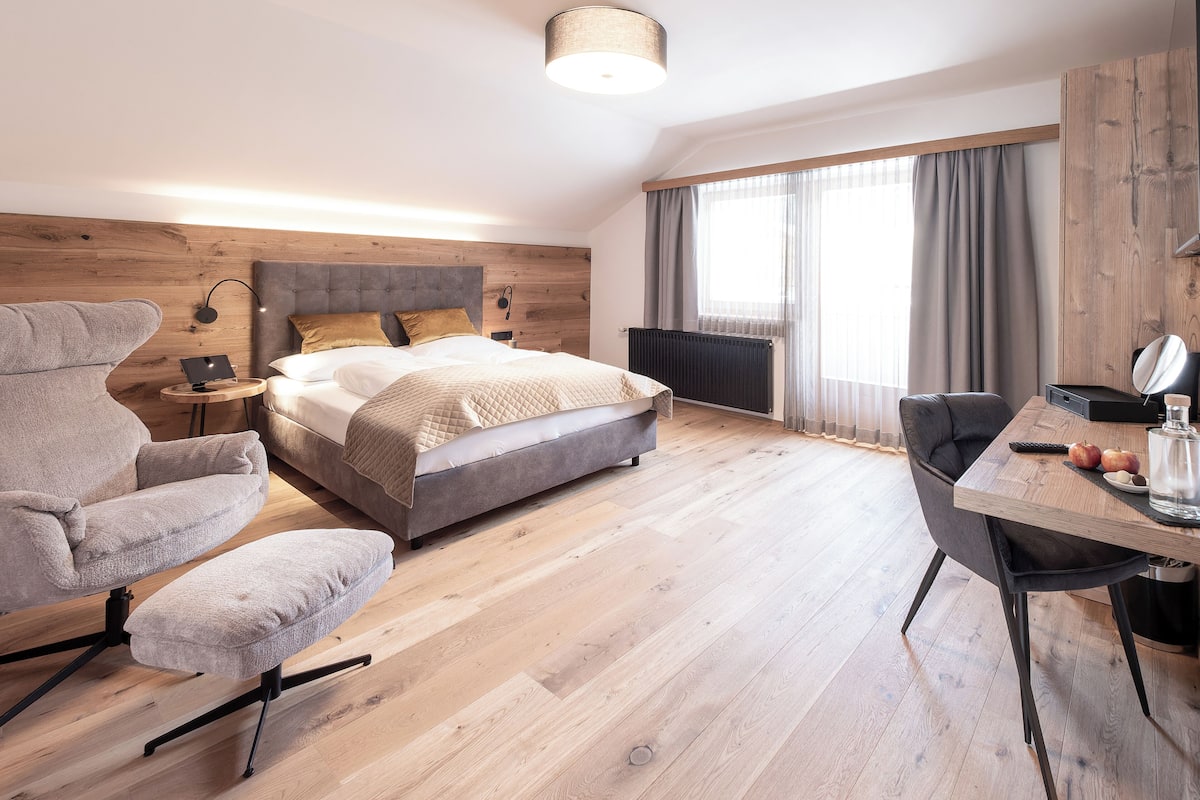 Un dormitorio moderno con una cama grande, un escritorio, una silla y una lámpara.