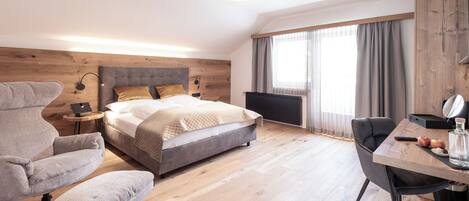 A modern bedroom with a large bed, a desk, a chair, and a lamp.