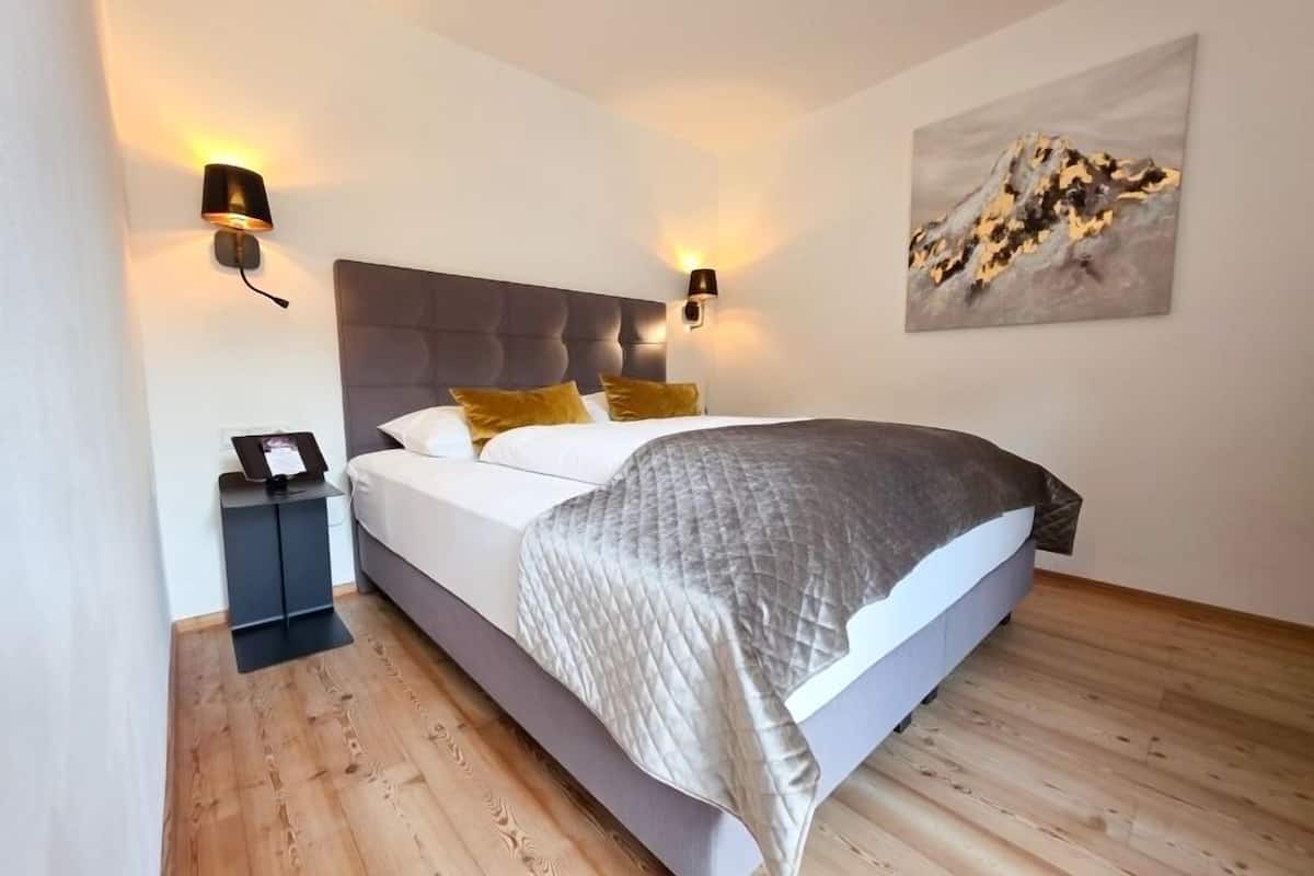 Un dormitorio moderno con una cama, lámparas de noche, una mesita de noche y un cuadro en la pared.