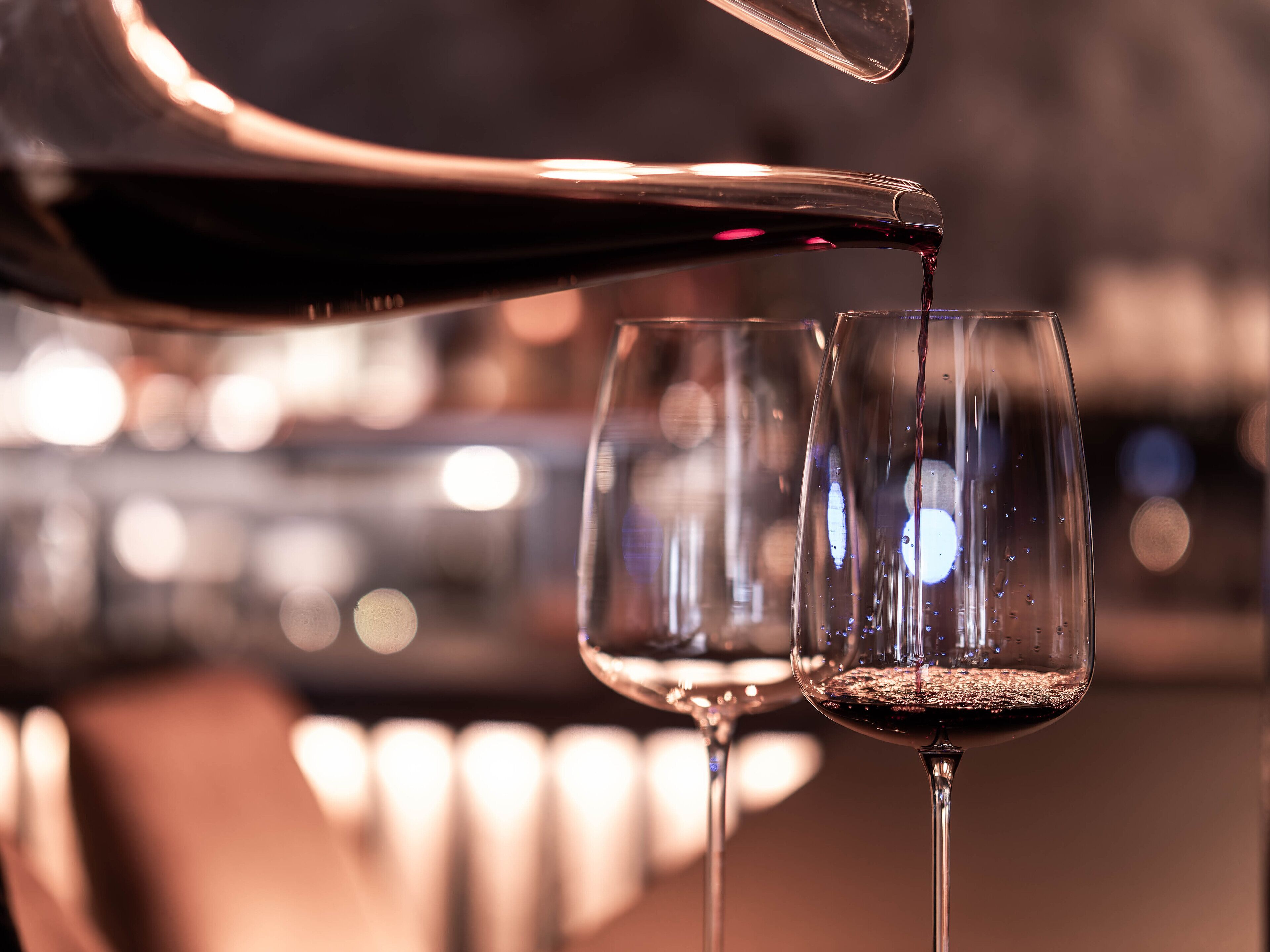A close-up of a wine glass being filled with red wine.