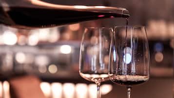A close-up of a wine glass being filled with red wine.