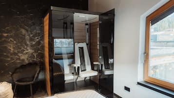 Una habitación moderna con cama, separador de vidrio, una silla y una ventana.