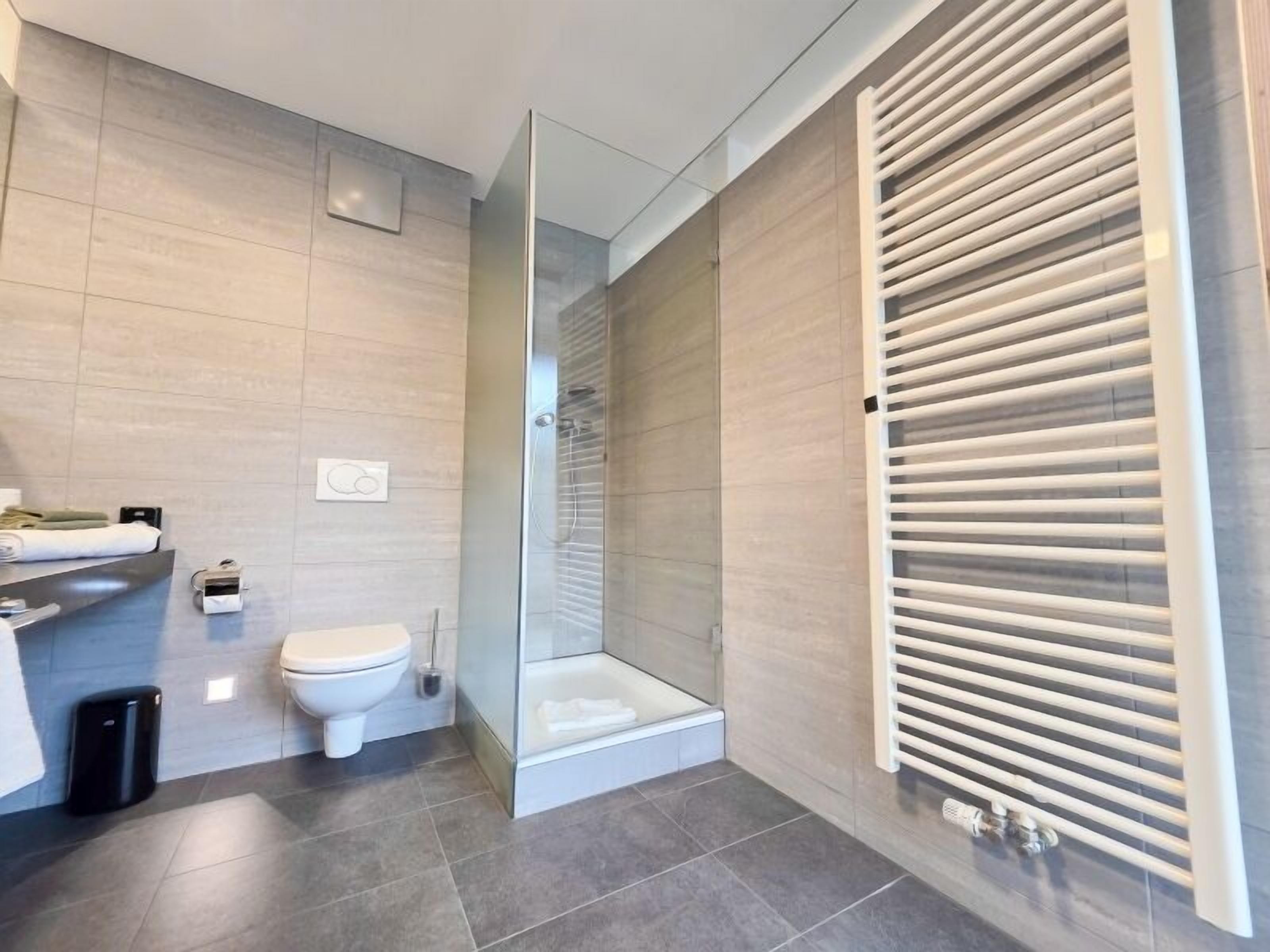 A modern bathroom with a toilet, shower, and a glass-enclosed shower area.