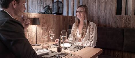 Un intérieur en bois avec une table à manger dressée pour deux personnes, agrémentée de verres à vin et de couverts.