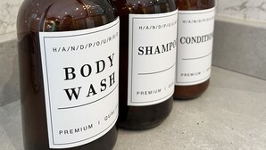 Three bottles of body wash, shampoo, and conditioner on a marble countertop. - Kingfisher Safari Tent (Droitwich)