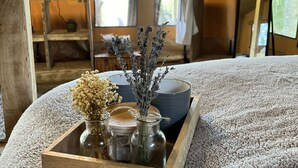 A cozy room with a wooden tray holding decorative items, a large window with a view of greenery, and a television on a wooden stand.