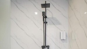 Uma casa de banho moderna com parede de mármore, um chuveiro e um porta-toalhas.