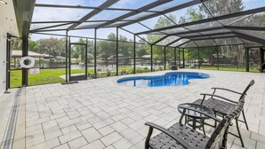 Et overdækket udendørs swimmingpool med udsigt over en park og en sø.