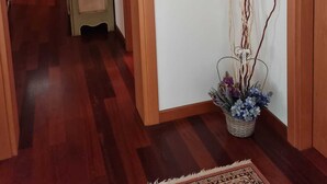 Ein Flur mit Holzboden, einer grünen Tür und einem Blumentopf mit blauen Blumen.