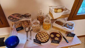 Ein Frühstücksbuffet mit verschiedenen Speisen, darunter Gebäck, Kekse und Marmeladen, präsentiert auf einem Tisch mit Schildern, die glutenfreie Optionen kennzeichnen.