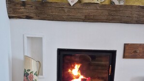 Ein Kamin mit Steinverkleidung, ein Holztisch mit Hirschschnitzerei und ein Regal mit Dekorationselementen.