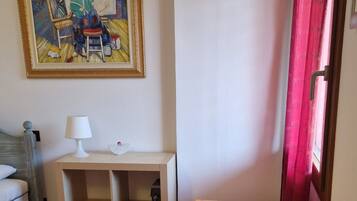 Een kamer met een houten tafel, een rood vloerkleed, een schilderij aan de muur en een raam met rode gordijnen.