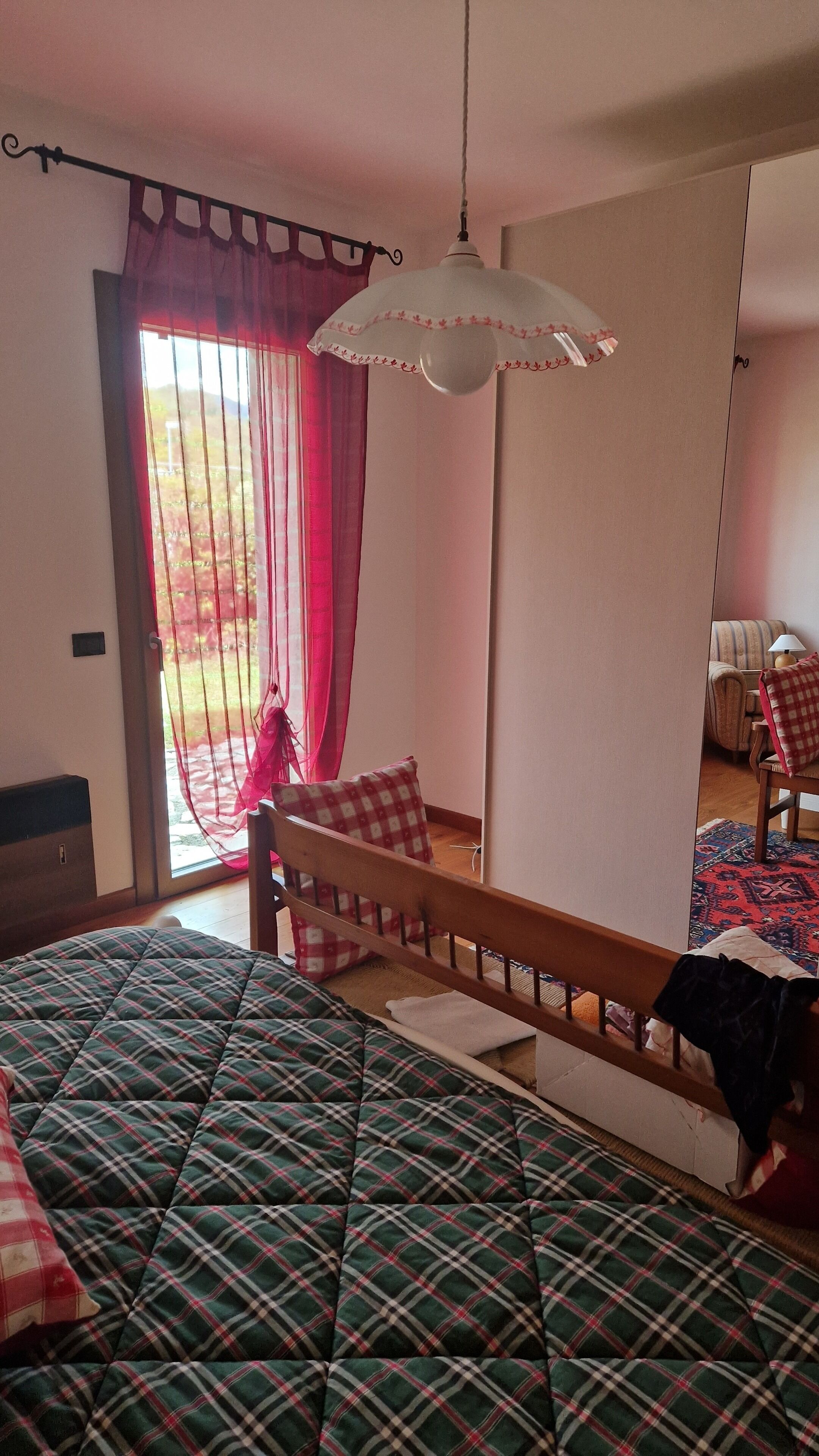 Ein Schlafzimmer mit einem Bett, einem Sessel, einer Lampe und einem Fenster mit Vorhängen.