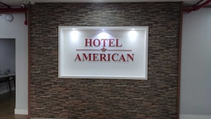 A sign for 'Hotel American' with a stone wall background. - Hotel American (Ariquemes)