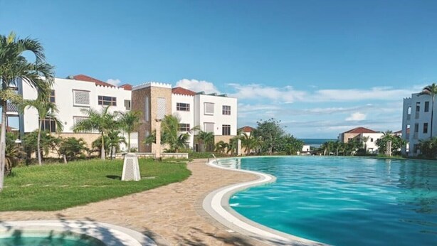 Un resort con piscina, palmeras y un cielo azul despejado.