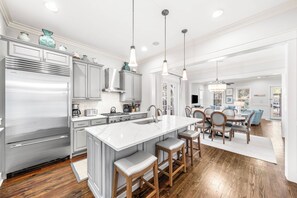 A modern kitchen with a large island, stainless steel appliances, and pendant lighting.