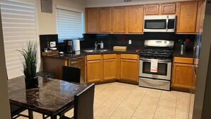 A kitchen with wooden cabinets, a microwave, stove, and a dining table with chairs.
