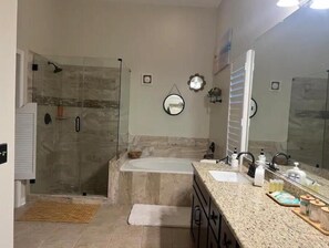 A modern bathroom with a walk-in shower, a freestanding bathtub, and a large vanity with a mirror.