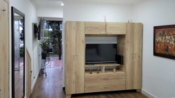 A room with a wooden entertainment unit, a flat-screen TV, and a painting on the wall.