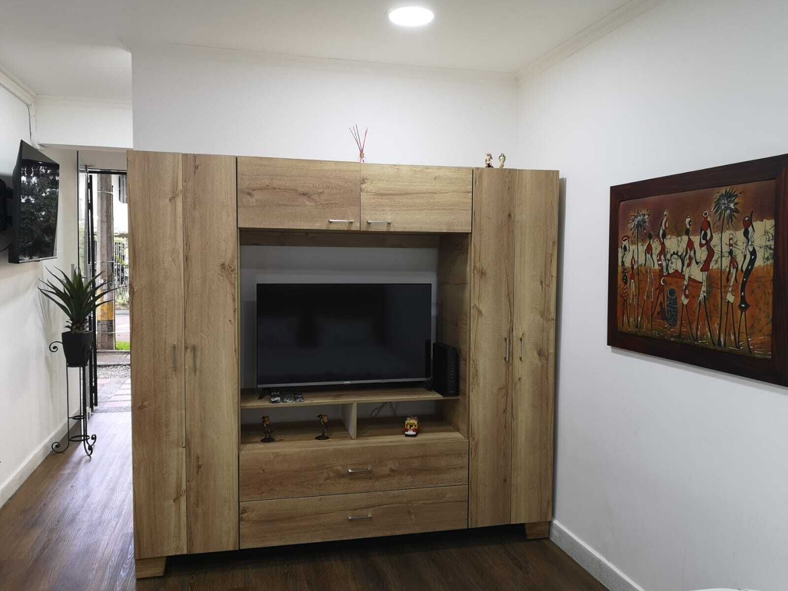 A wooden entertainment unit with a flat-screen TV, drawers, and a shelf with decorative items.