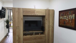 A wooden entertainment unit with a flat-screen TV, drawers, and a shelf with decorative items.