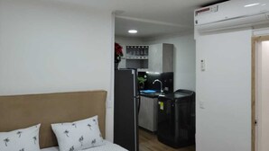A compact room with a bed, a kitchenette, and a small bathroom.